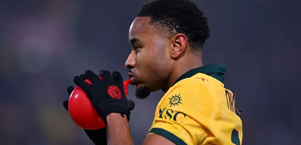 Jugador soplando un globo rojo en el campo