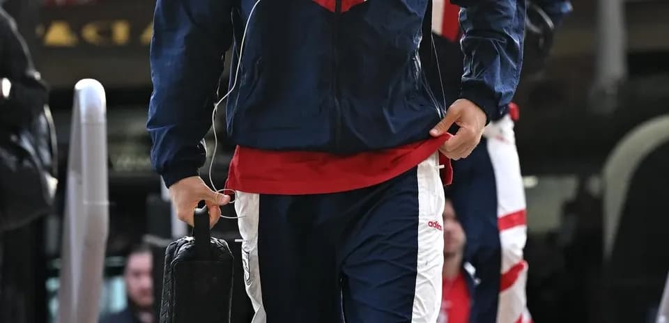 Jugador entrando con traje de entrenamiento y auriculares