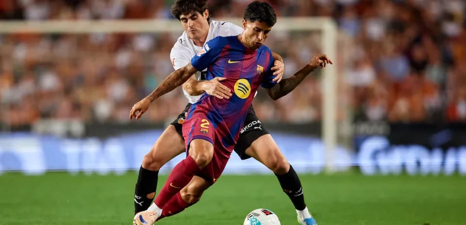 Jugador de Barcelona driblando mientras es marcado