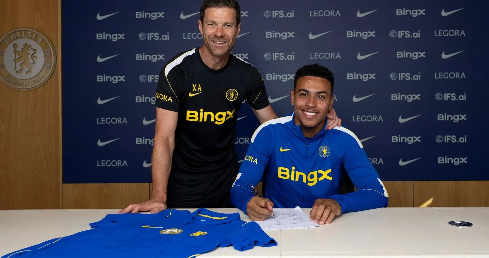 Jugador firmando contrato con el entrenador en Chelsea