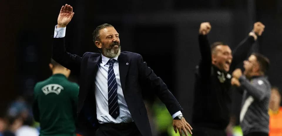 Entrenador celebrando con brazos alzados durante partido