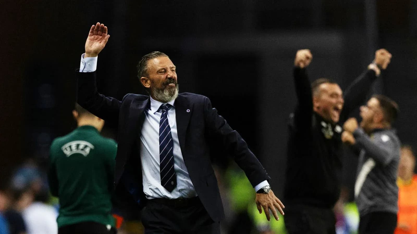 Entrenador celebrando con brazos alzados durante partido