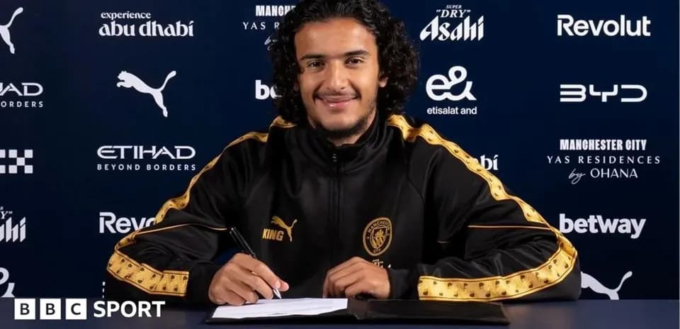 Jugador firmando contrato en mesa de prensa