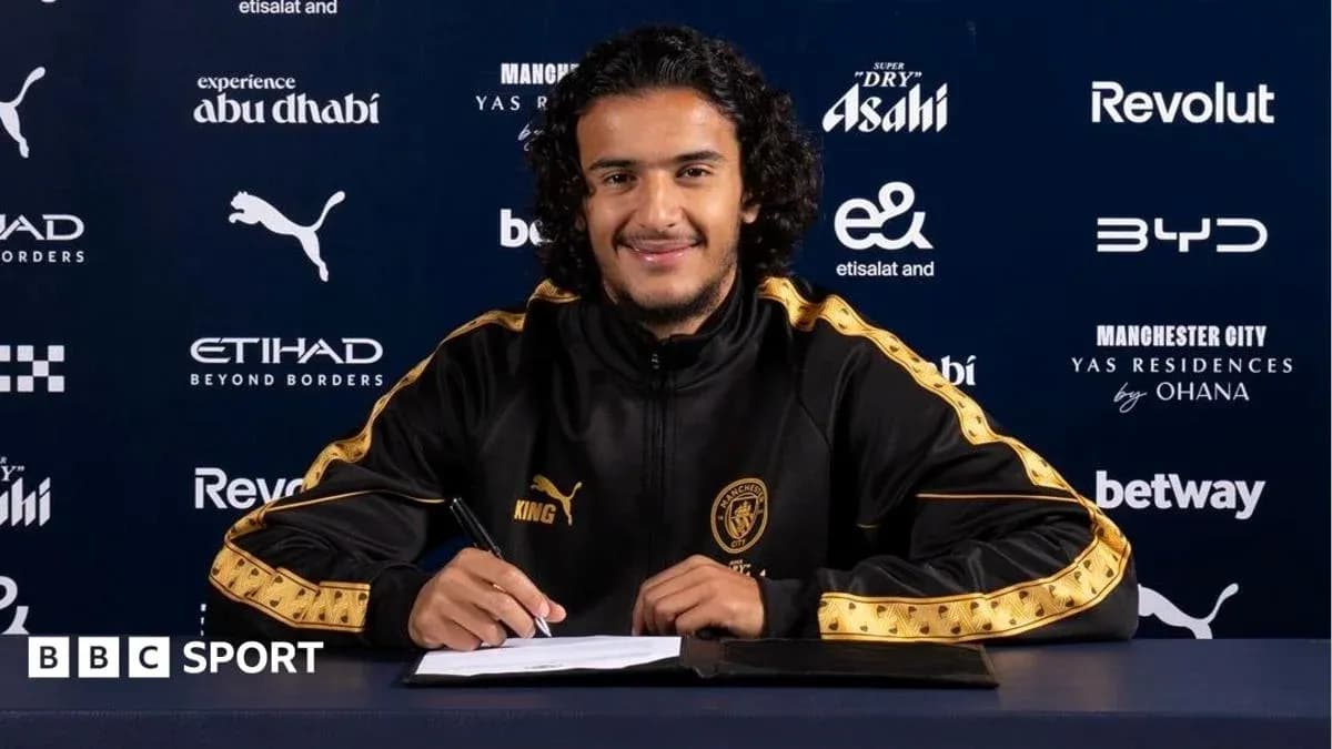 Jugador firmando contrato en mesa de prensa