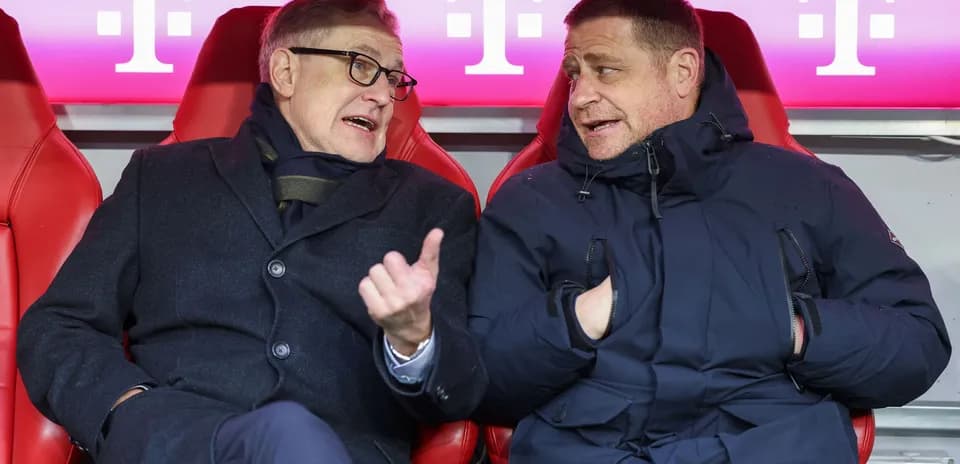Dos hombres conversando en el banquillo del estadio