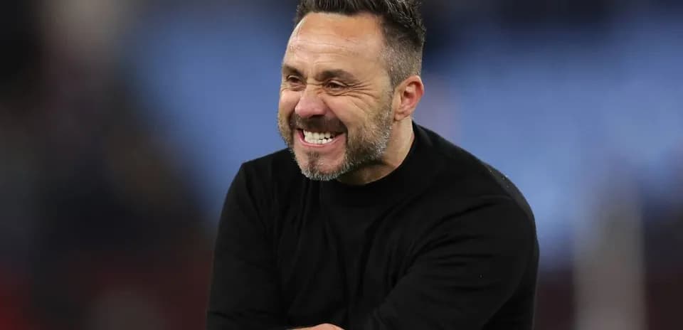 Entrenador sonriendo en el campo durante el partido