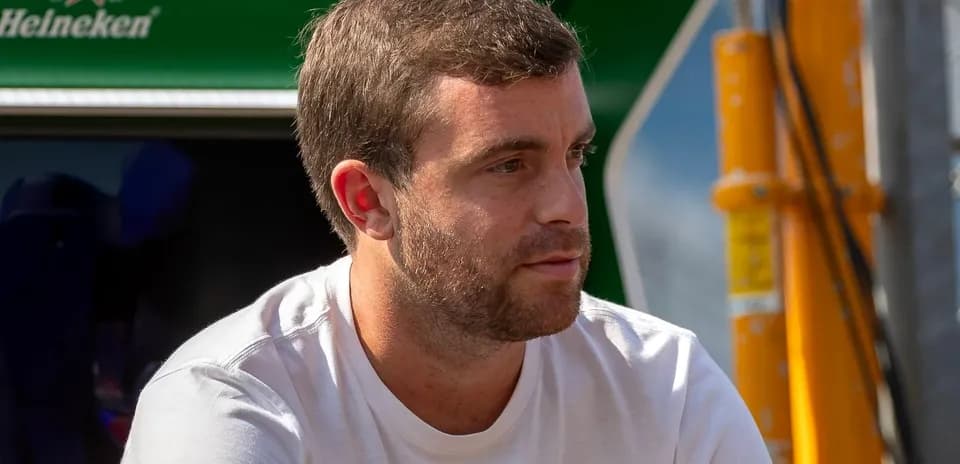 Hombre sentado en el paddock con fondo verde