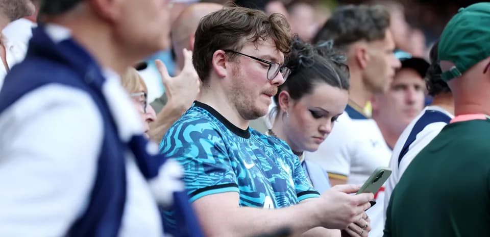 Aficionados revisando sus teléfonos en el estadio