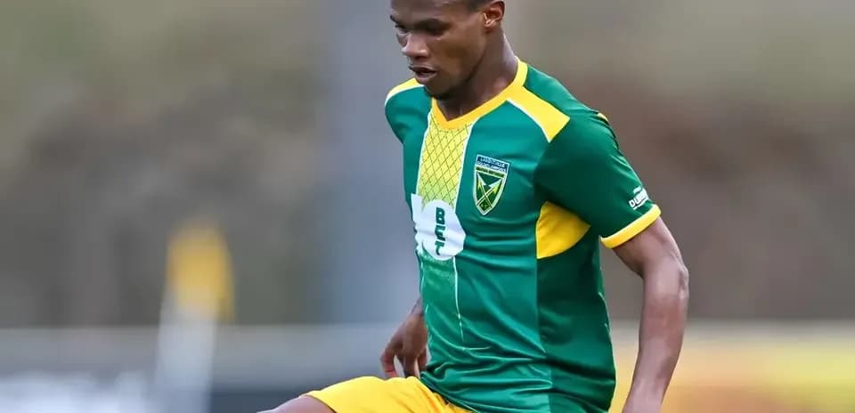 Jugador de fútbol en acción con uniforme verde y amarillo