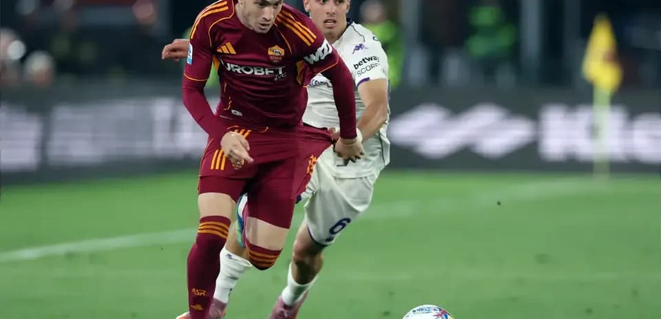 Jugador de la Roma driblando mientras es seguido por oponente