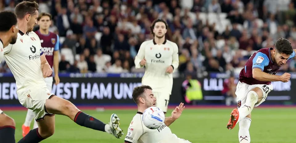 Jugador de West Ham chutando mientras rival cae al suelo
