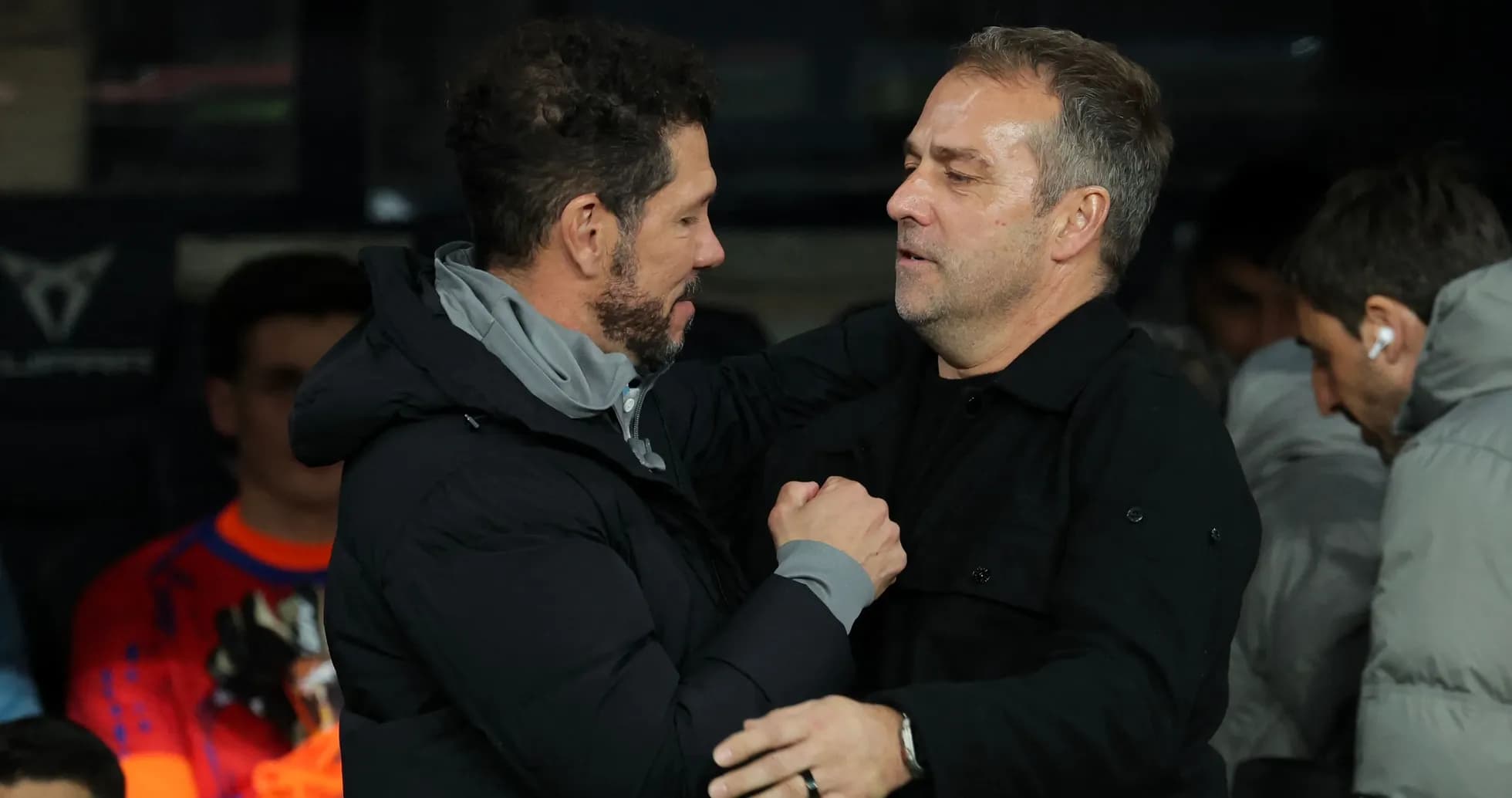 Entrenadores saludándose en el banquillo durante el partido