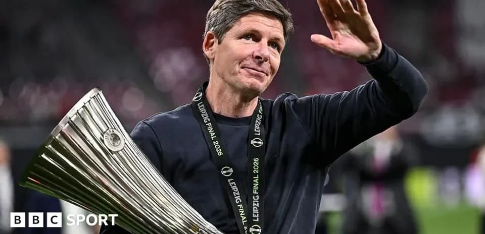 Entrenador sosteniendo trofeo y saludando tras el partido