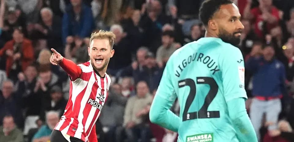 Jugador señalando tras anotar gol, portero en fondo