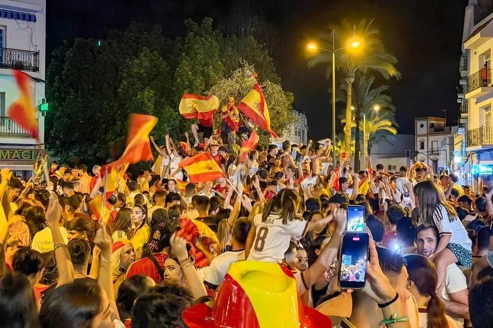 Multitud celebrando con banderas españolas en la calle
