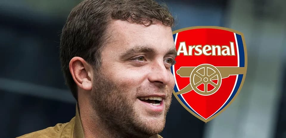 Hombre sonriendo con el escudo de Arsenal detrás