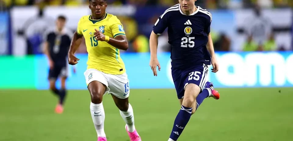 Jugador de Escocia corriendo con el balón, seguido por jugador brasileño