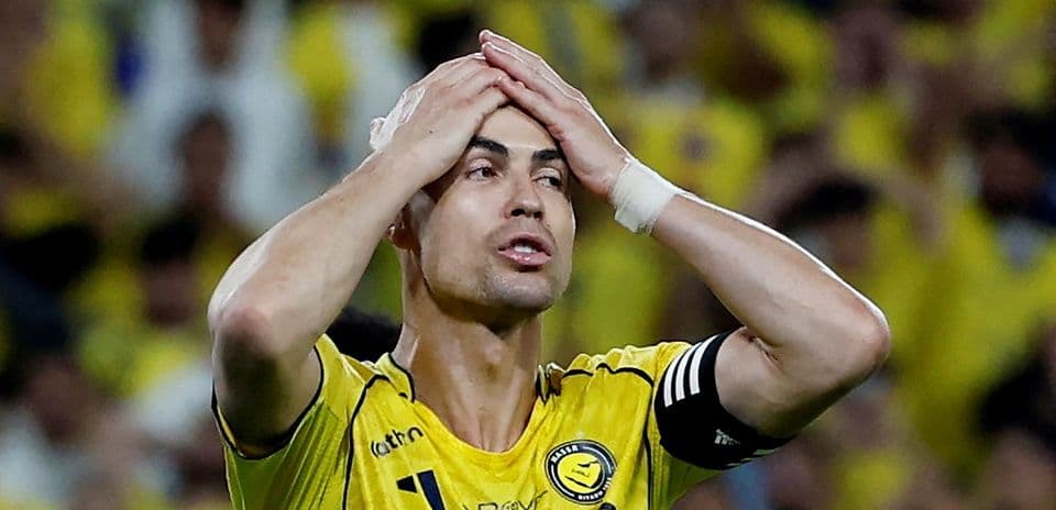 Jugador con camiseta amarilla sostiene su cabeza en frustración