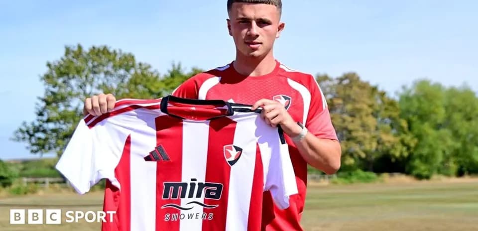 Jugador sosteniendo camiseta de Cheltenham Town FC