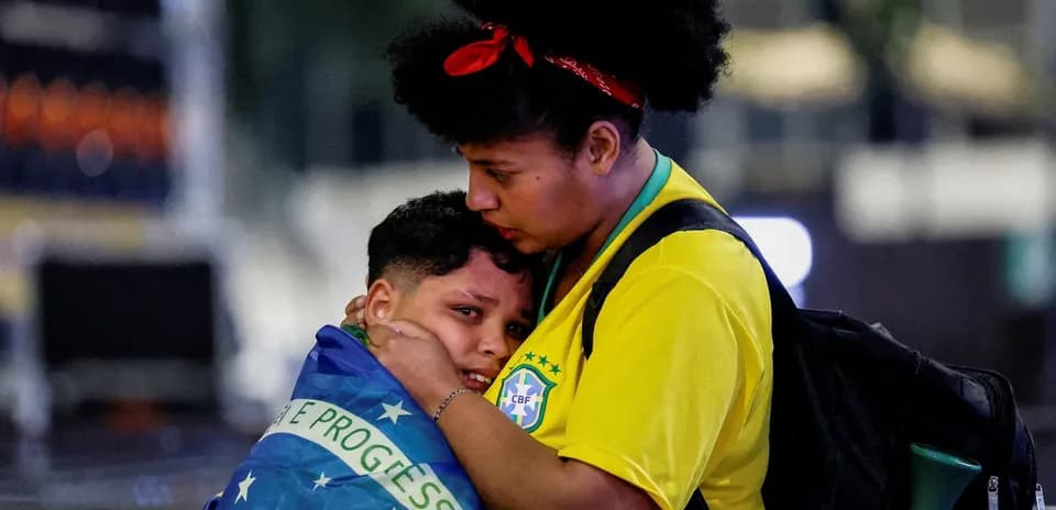 Mujer abrazando a un niño envuelto en bandera brasileña