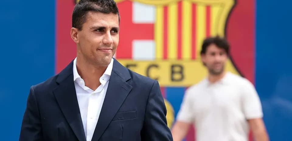 Jugador de fútbol posando frente al escudo del FC Barcelona