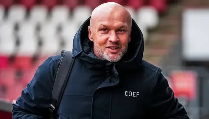 Entrenador llegando al estadio con abrigo oscuro