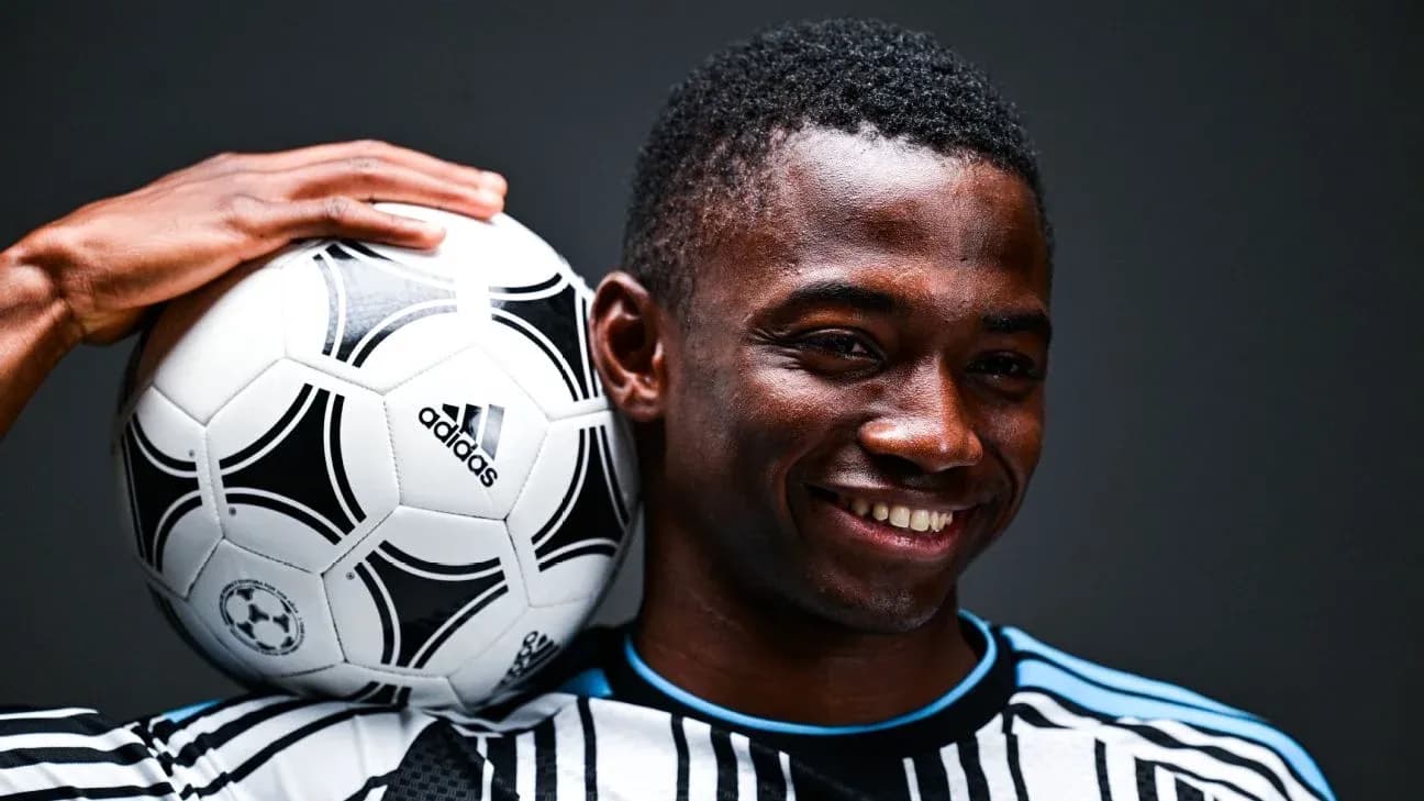 Jugador sosteniendo un balón de fútbol sobre su hombro Jugador sosteniendo un balón de fútbol sobre su hombro
