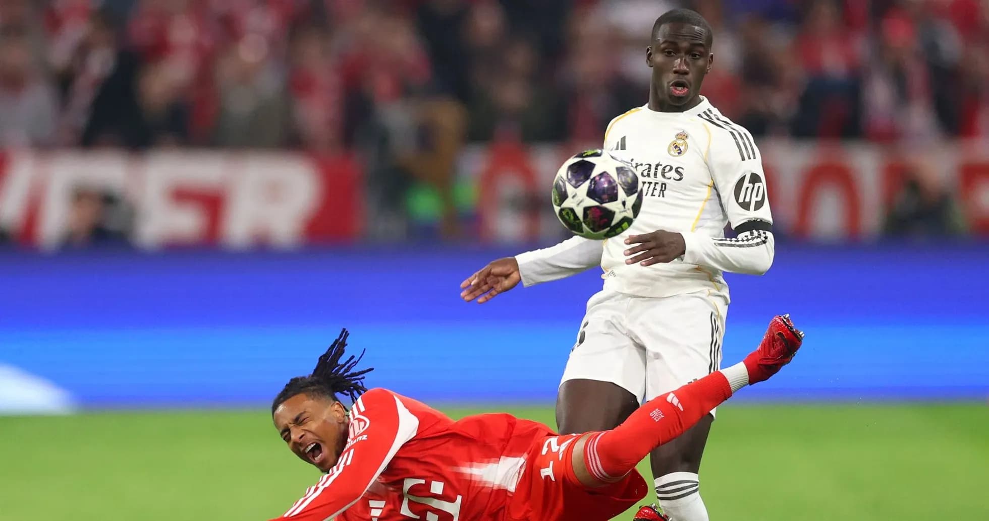 Jugador de Real Madrid controla el balón mientras rival cae Jugador de Real Madrid controla el balón mientras rival cae