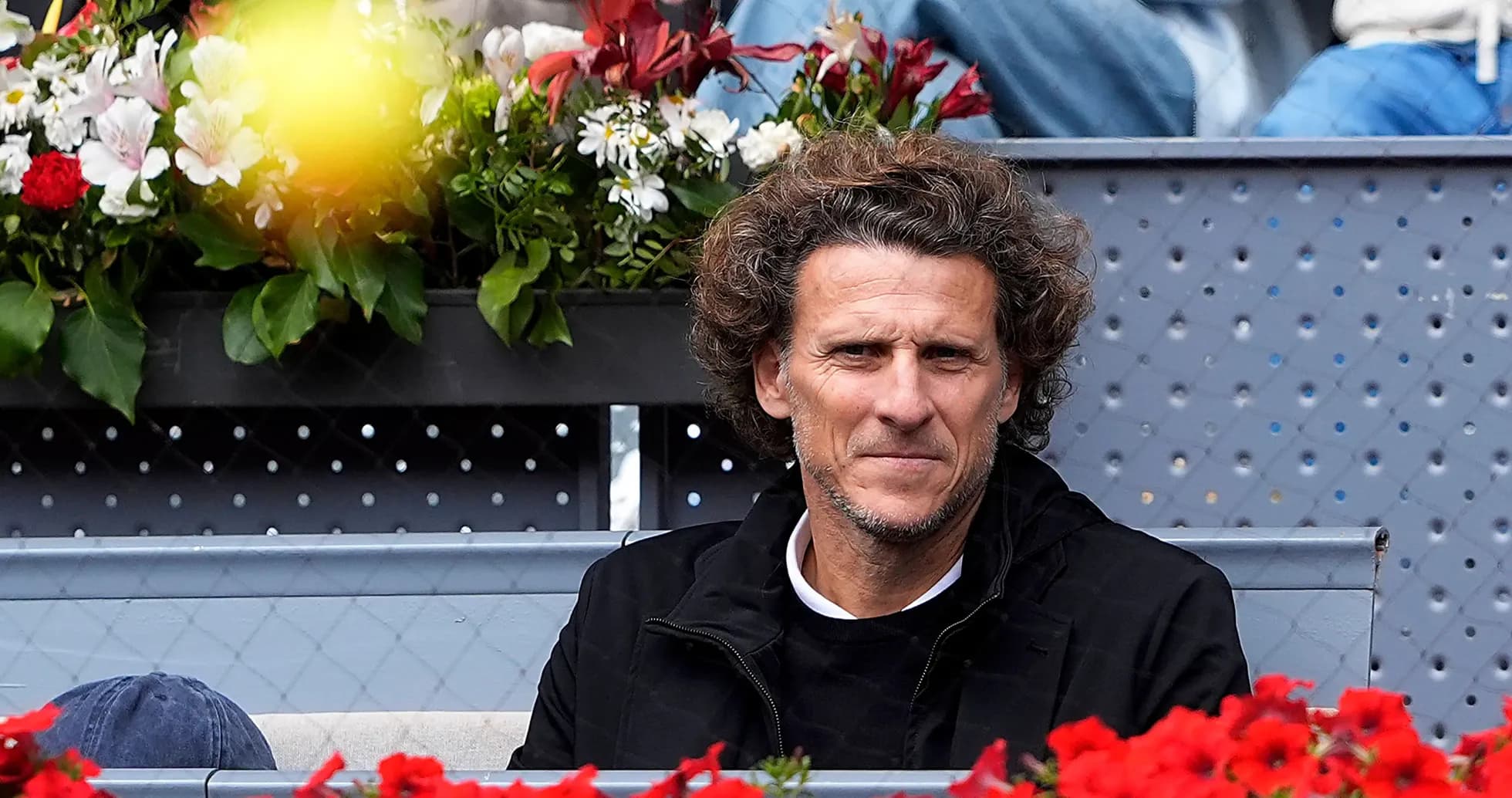 Hombre sentado en gradas con flores en el fondo Hombre sentado en gradas con flores en el fondo