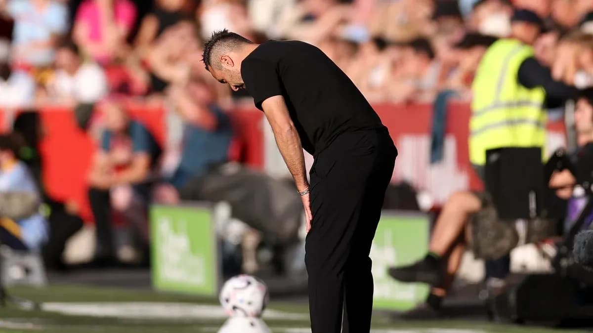 Entrenador agachado junto a balón en la línea de banda Entrenador agachado junto a balón en la línea de banda