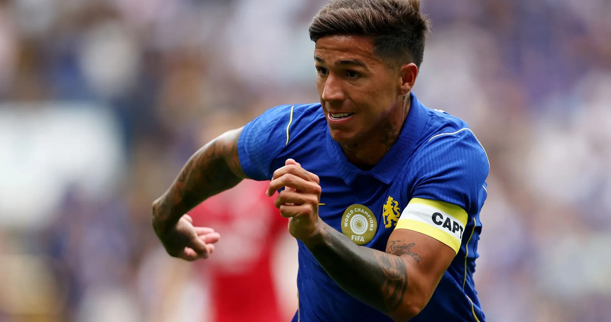 Jugador corriendo con camiseta azul y cinta de capitán Jugador corriendo con camiseta azul y cinta de capitán
