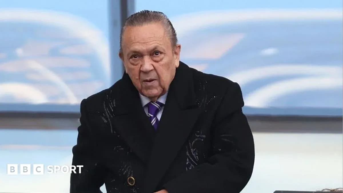 Hombre con abrigo oscuro en un evento deportivo Hombre con abrigo oscuro en un evento deportivo