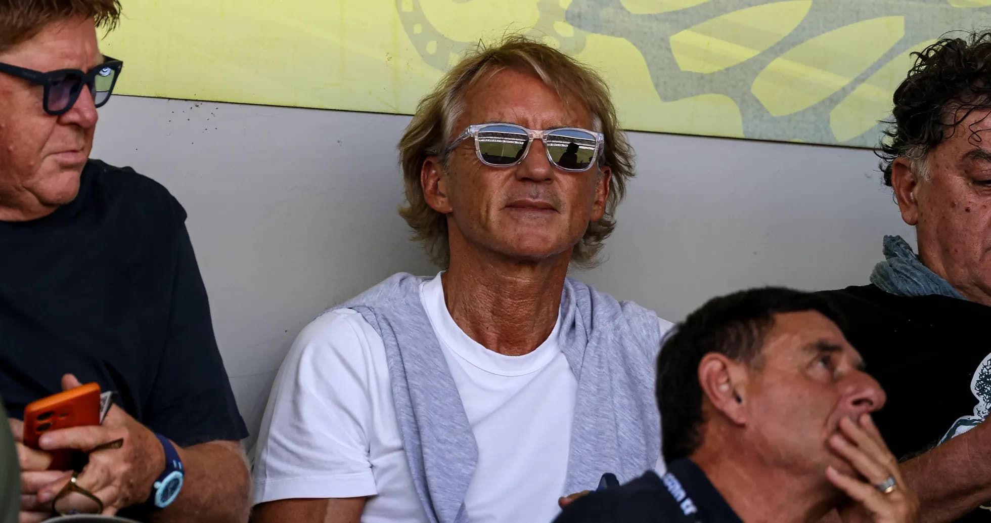 Hombre con gafas sentado en un evento deportivo Hombre con gafas sentado en un evento deportivo