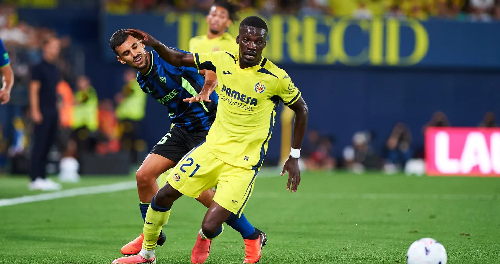 Jugador de Villarreal luchando por el balón contra rival Jugador de Villarreal luchando por el balón contra rival
