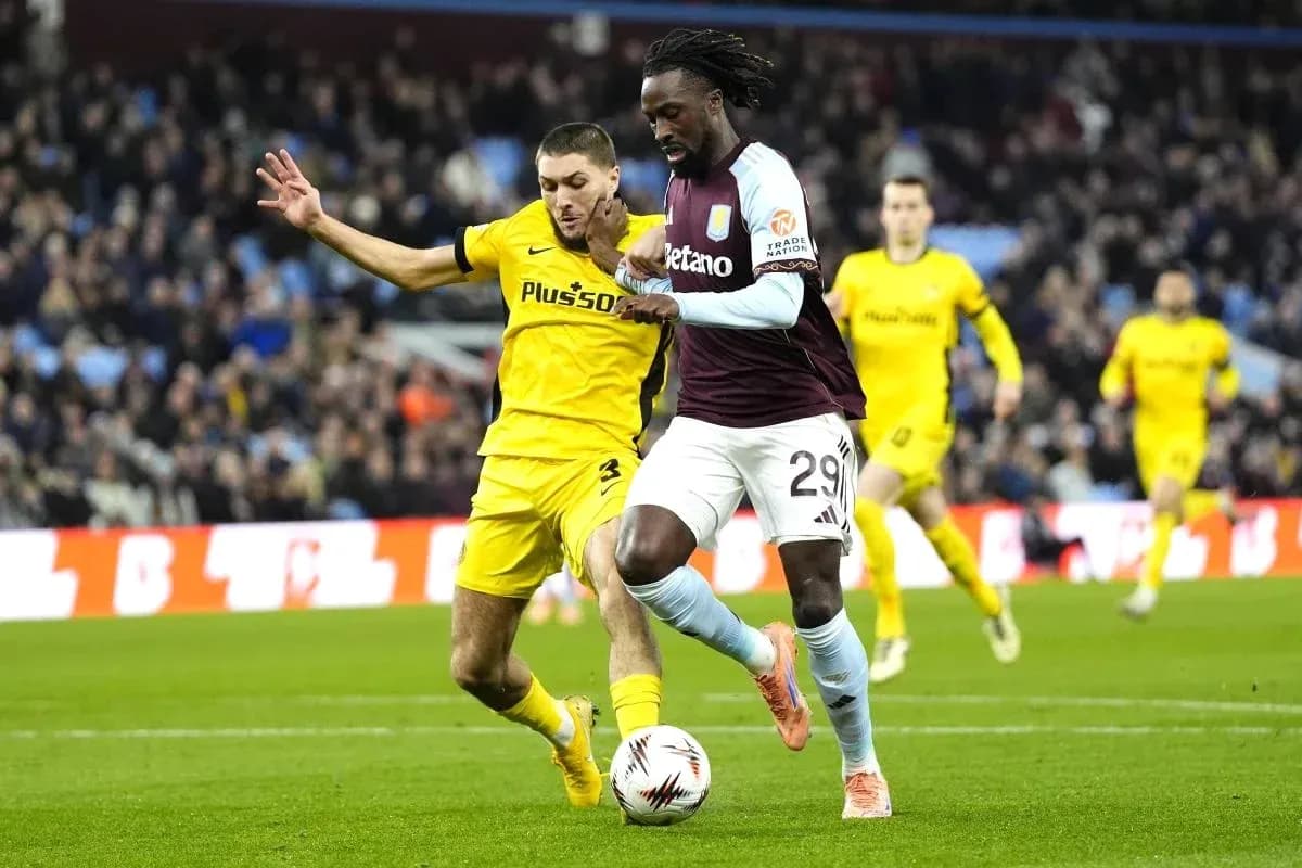 Jugador de Aston Villa driblando mientras es marcado Jugador de Aston Villa driblando mientras es marcado