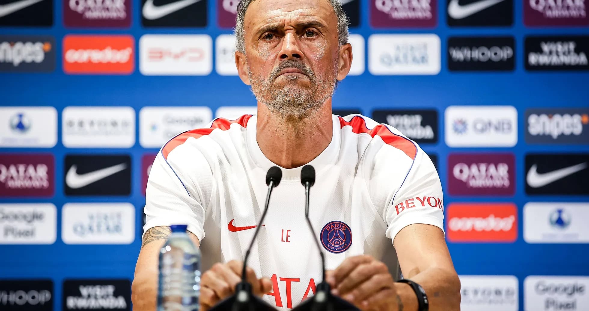 Entrenador en conferencia de prensa con logotipo de PSG Entrenador en conferencia de prensa con logotipo de PSG