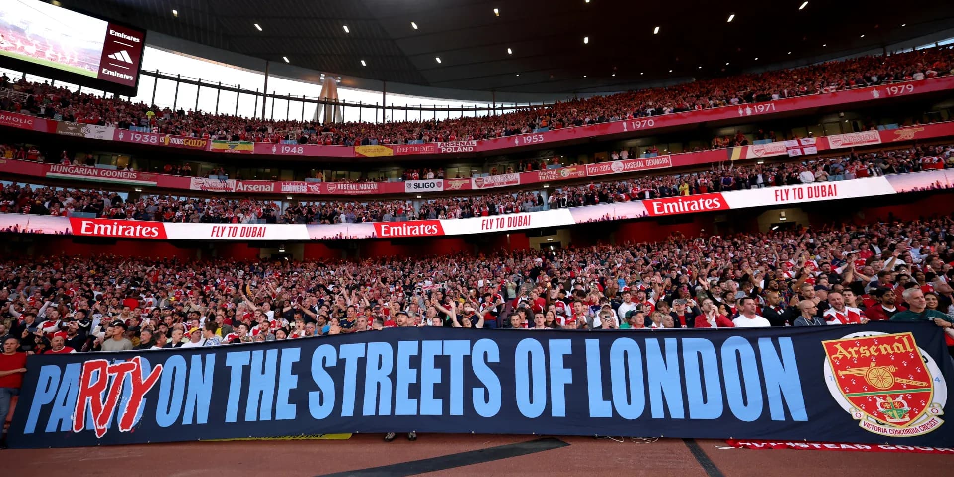 Aficionados de Arsenal sosteniendo una pancarta en el estadio Aficionados de Arsenal sosteniendo una pancarta en el estadio