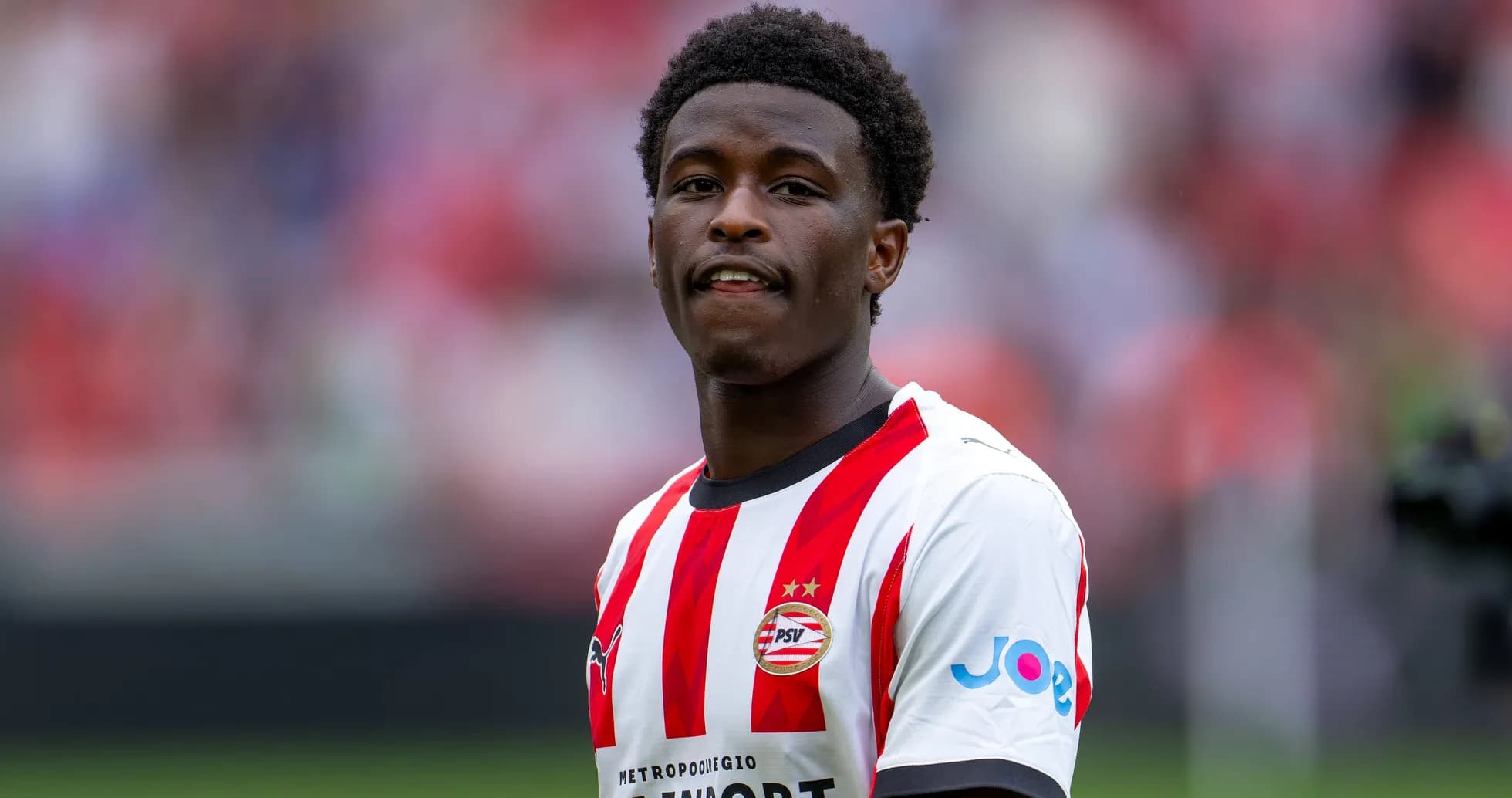 Jugador de PSV con camiseta roja y blanca sonriendo Jugador de PSV con camiseta roja y blanca sonriendo