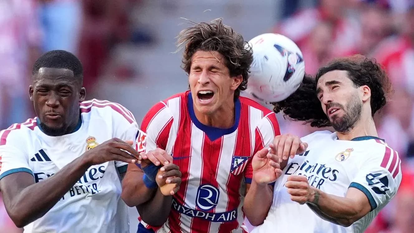 Jugadores de Atlético y Real Madrid luchando por el balón Jugadores de Atlético y Real Madrid luchando por el balón