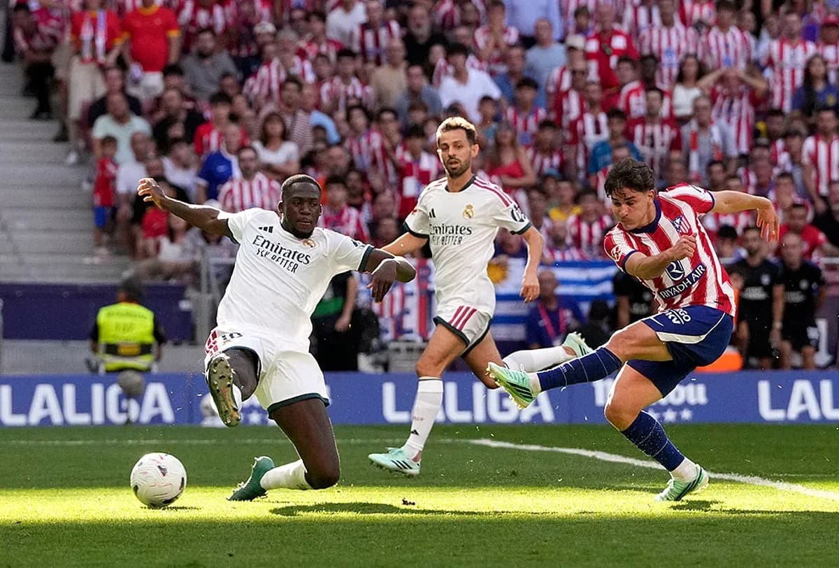 Jugador de Atlético Madrid dispara ante defensa rival Jugador de Atlético Madrid dispara ante defensa rival