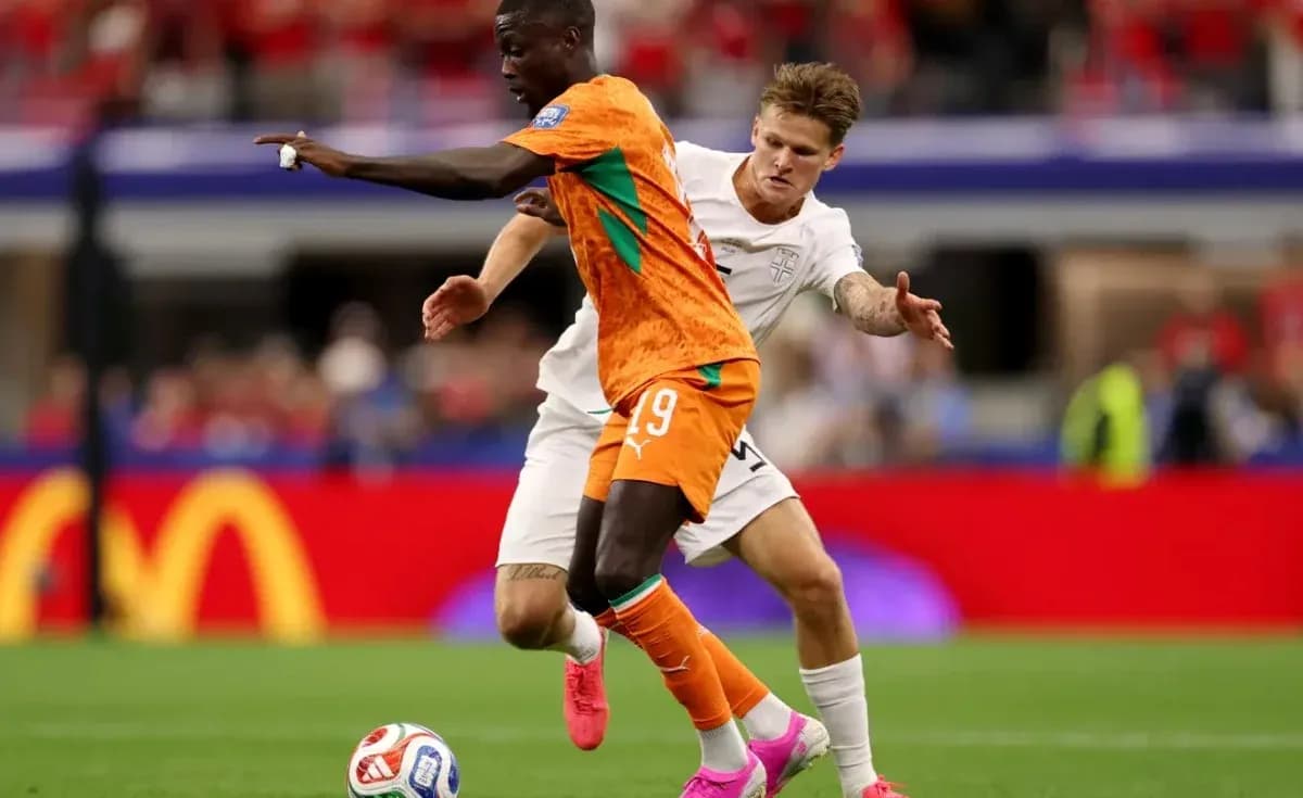 Jugador con camiseta naranja driblando a oponente en campo Jugador con camiseta naranja driblando a oponente en campo