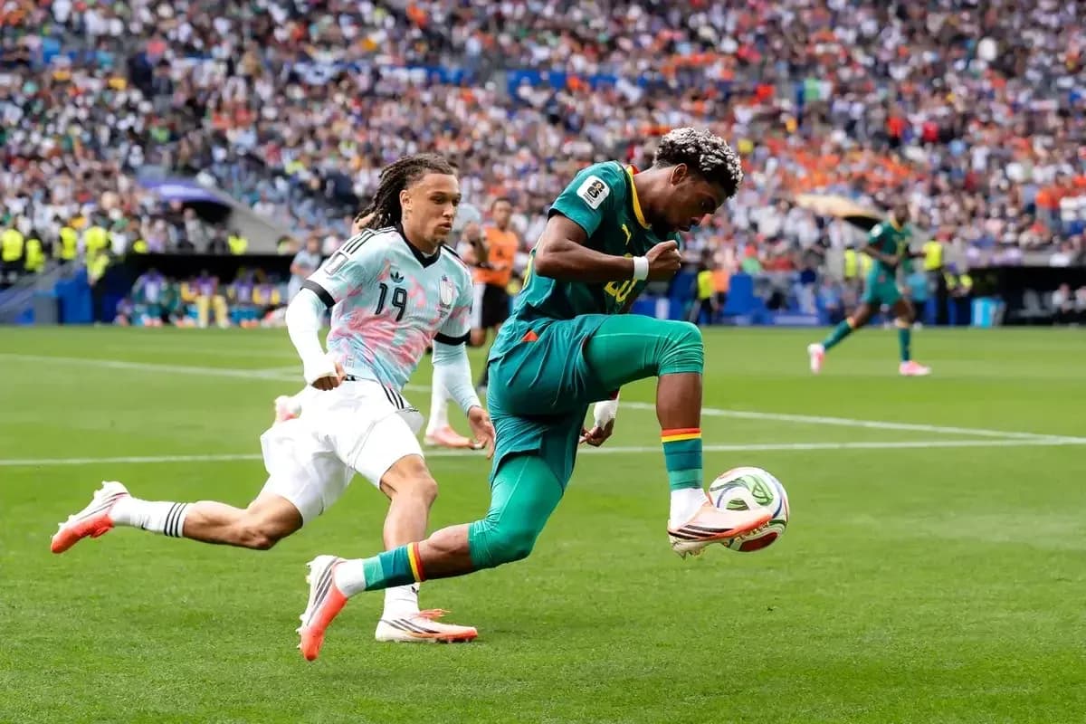 Jugador de Camerún controla el balón mientras es perseguido Jugador de Camerún controla el balón mientras es perseguido