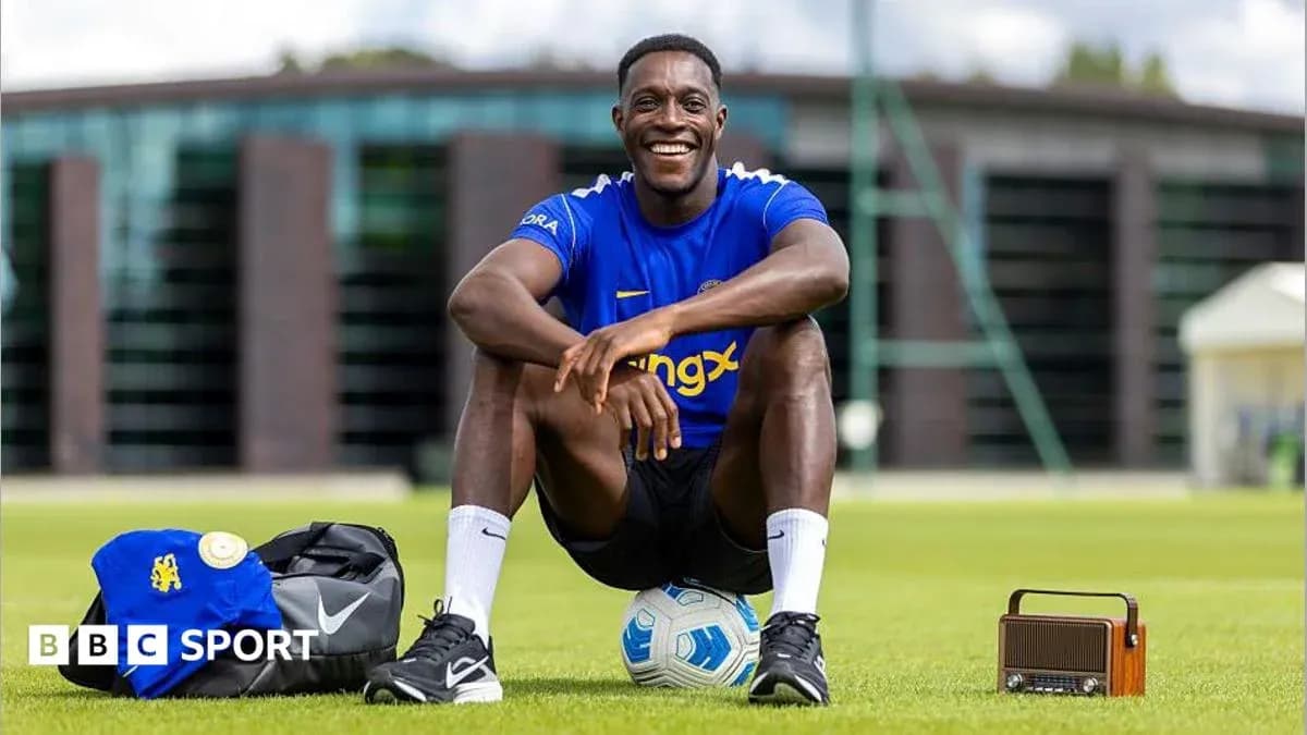 Jugador sentado en campo de entrenamiento con balón Jugador sentado en campo de entrenamiento con balón
