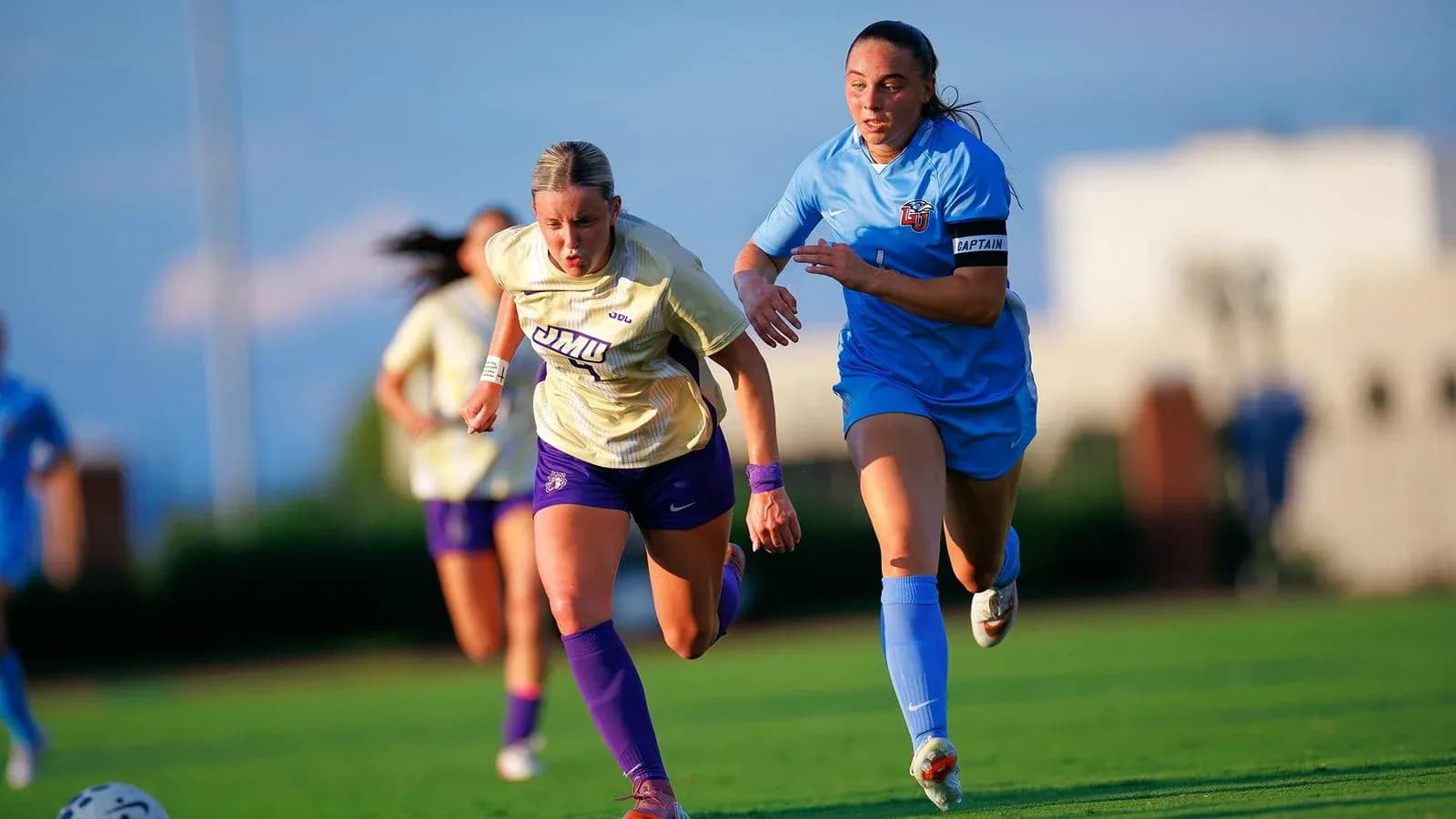 Jugadora de JMU persiguiendo balón en campo de fútbol Jugadora de JMU persiguiendo balón en campo de fútbol