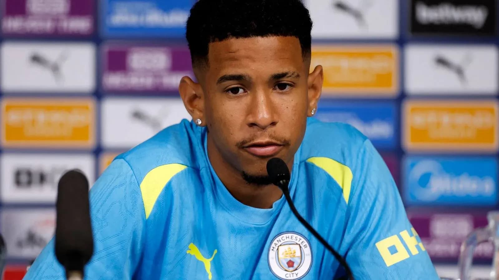 Jugador en rueda de prensa con camiseta de Manchester City Jugador en rueda de prensa con camiseta de Manchester City
