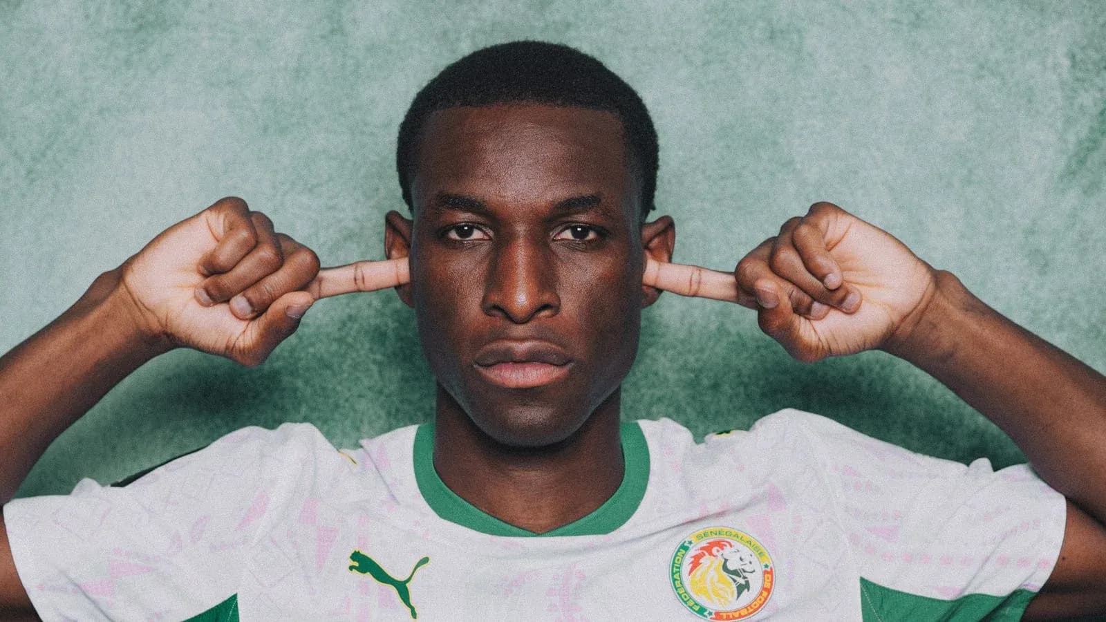 Jugador de fútbol con camiseta de Senegal tapándose los oídos Jugador de fútbol con camiseta de Senegal tapándose los oídos