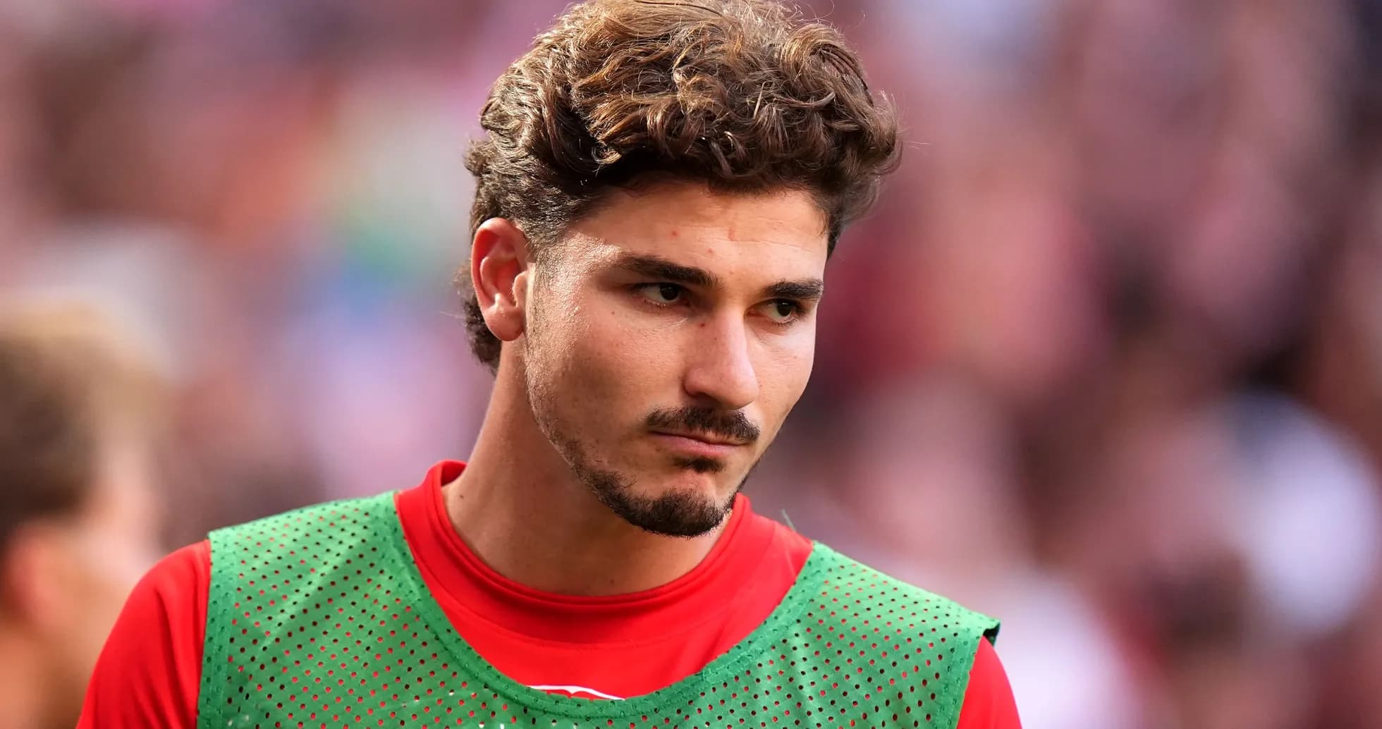 Jugador en la banca con camiseta roja y chaleco verde Jugador en la banca con camiseta roja y chaleco verde