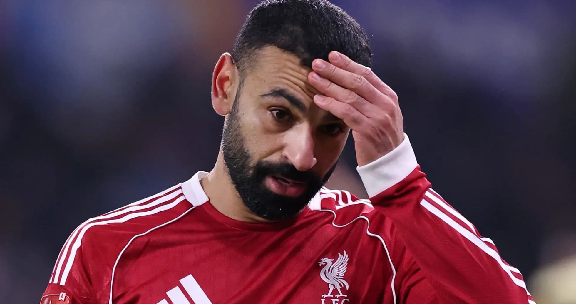 Jugador de Liverpool con camiseta roja, tocándose la frente Jugador de Liverpool con camiseta roja, tocándose la frente