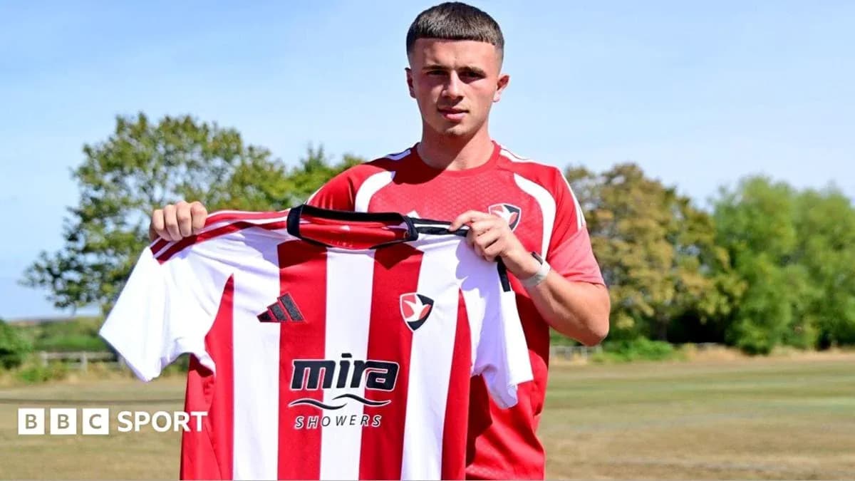 Jugador sosteniendo camiseta de Cheltenham Town FC Jugador sosteniendo camiseta de Cheltenham Town FC
