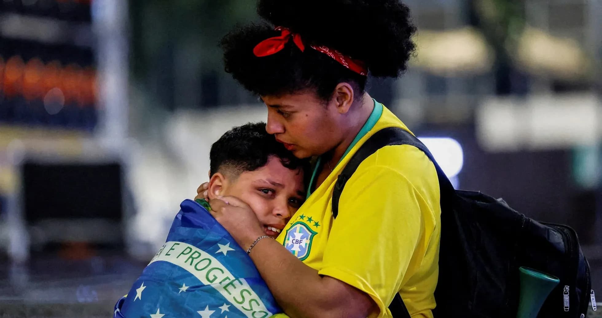 Mujer abrazando a un niño envuelto en bandera brasileña Mujer abrazando a un niño envuelto en bandera brasileña